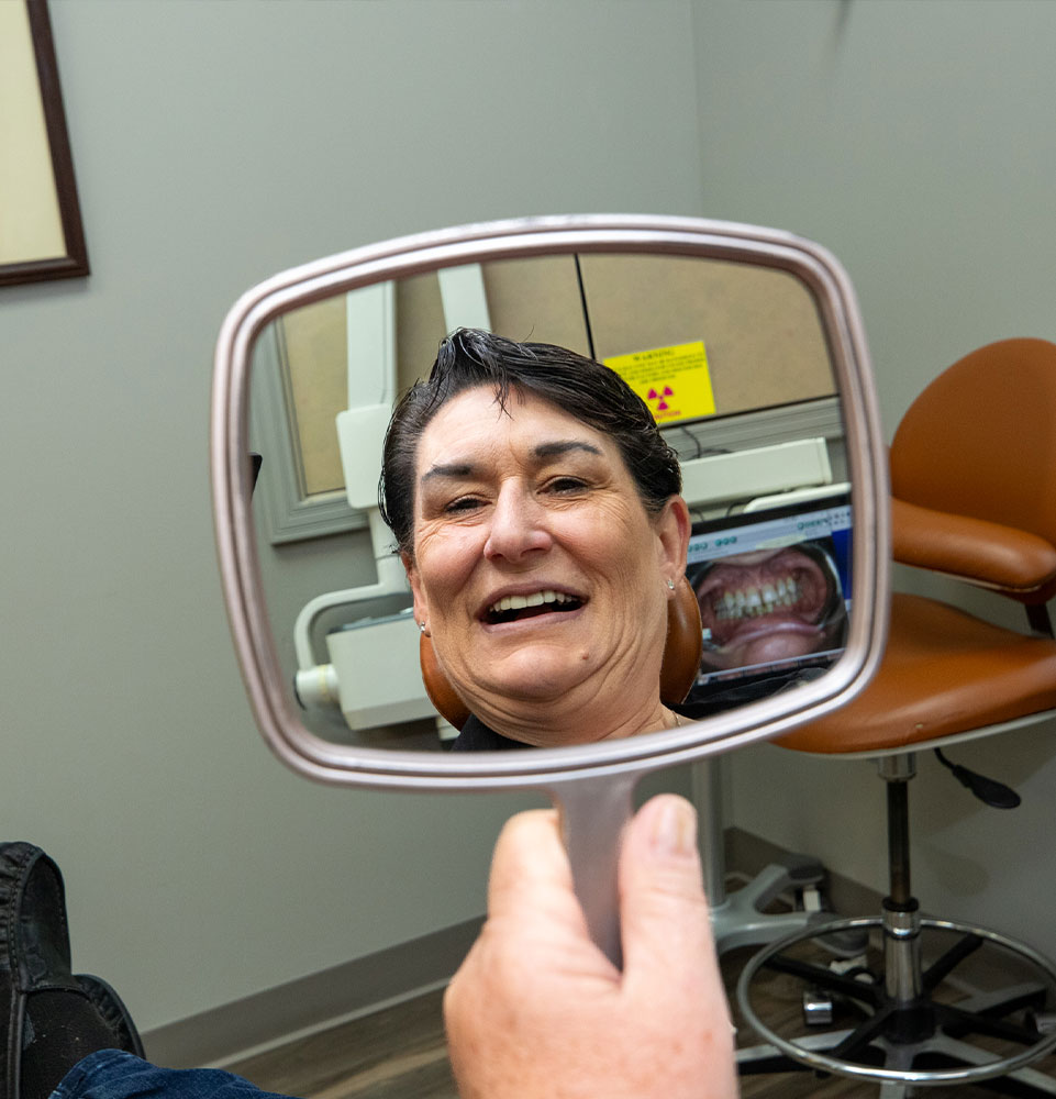 patient looking in the mirror and smiling confidently after their dental procedure
