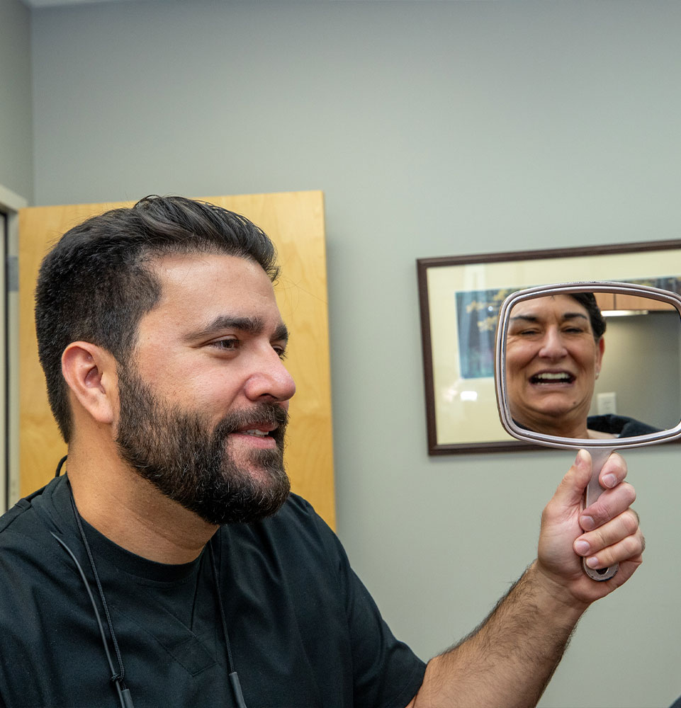 doctor showing patient mirror to show smile after dental procedure