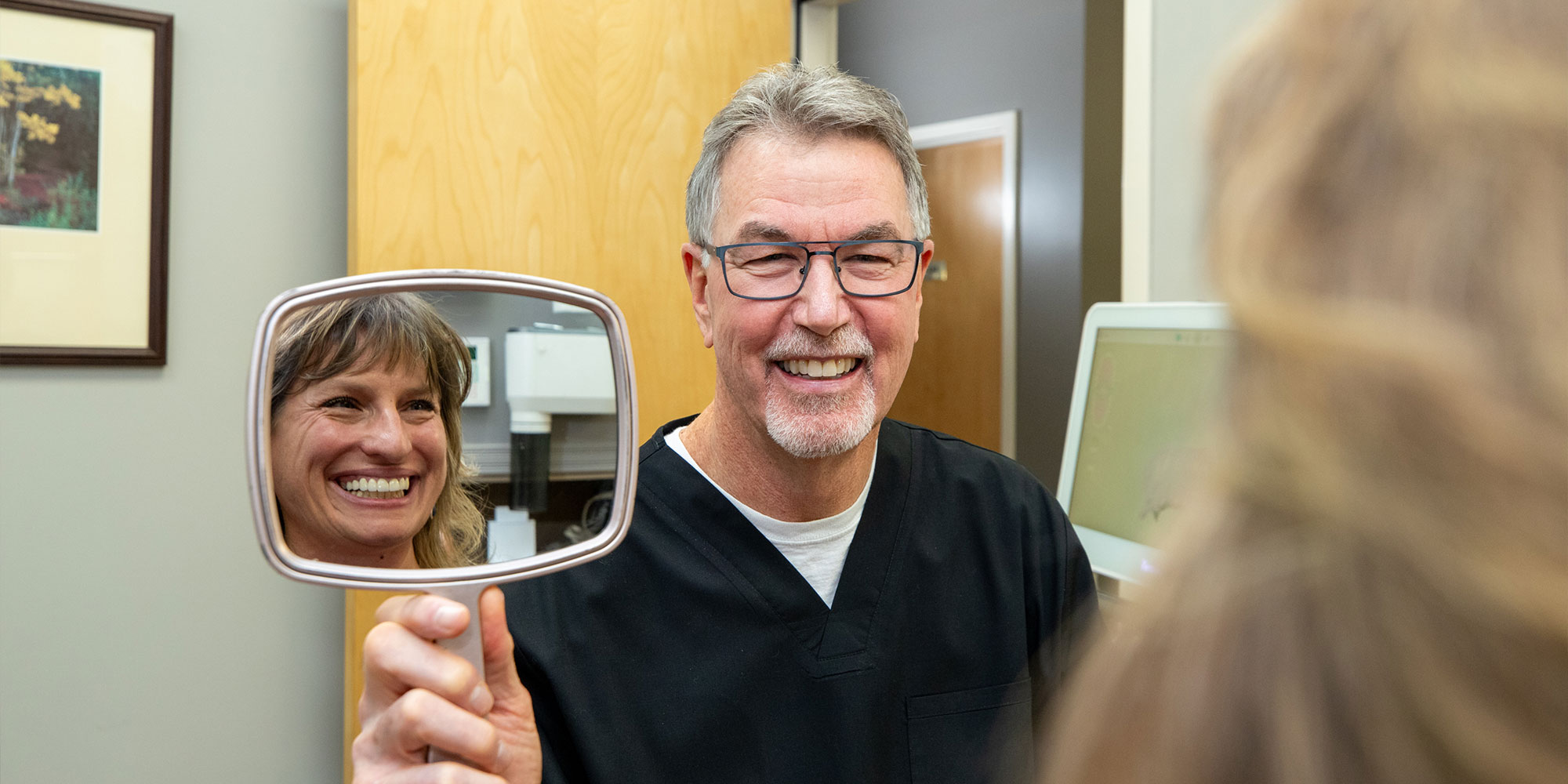 patient being shown mirror and smiling confidently after their dental procedure